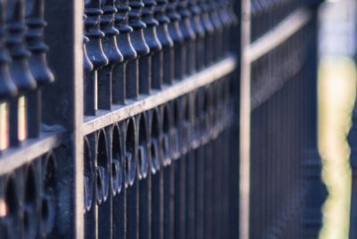 A vertical closeup shot of a metal fence on a sidewalk